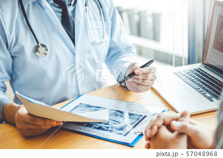 Dentist talking to male patient and presenting Dentist talking to male patient and presenting 57048968