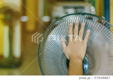 Hand of Young man touch and adjust  on front grills of electric fan for a good wind 57049867