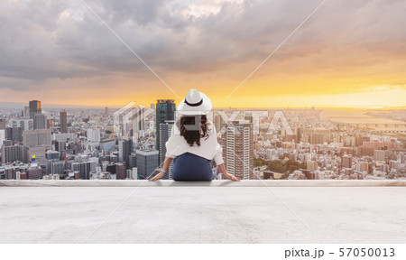 Young woman in white hat with Osaka city in sunset 57050013