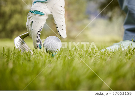 Hand in glove placing golf ball on tee 57053159