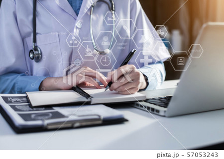 Young female in uniform of doctor using digital technology laptop for Output Device and writing a patient report on the office desk. 57053243