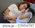 Mother and daughter laying on sofa and talking 57054797