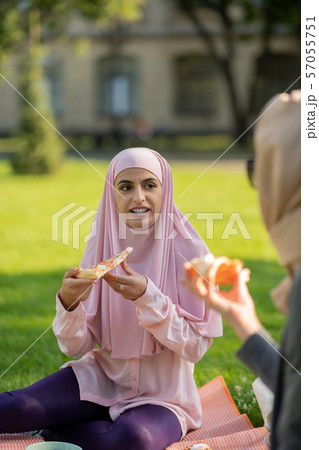 Dark-eyed muslim woman eating pizza with friend 57055751