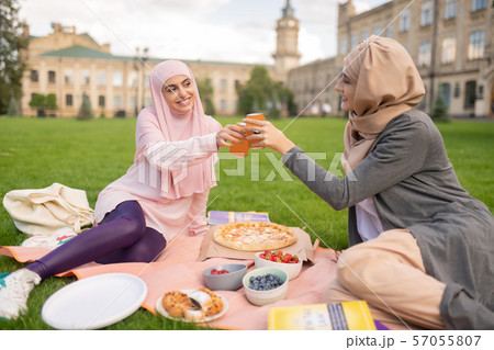 Cheerful muslim students enjoying pizza time outside 57055807