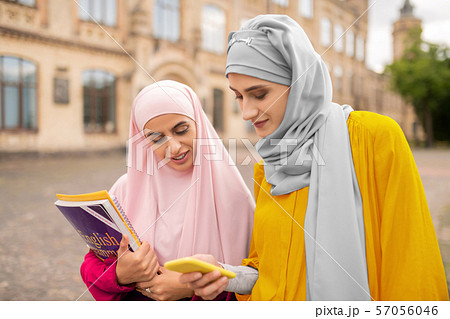 Best friend showing photo on smartphone to muslim student 57056046