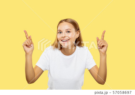 Caucasian young woman's half-length portrait on yellow background Caucasian young woman's half-length portrait on yellow background 57058697