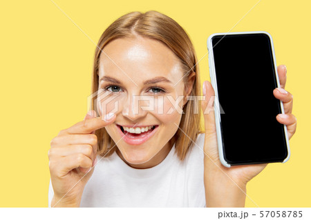 Caucasian young woman's half-length portrait on yellow background Caucasian young woman's half-length portrait on yellow background 57058785