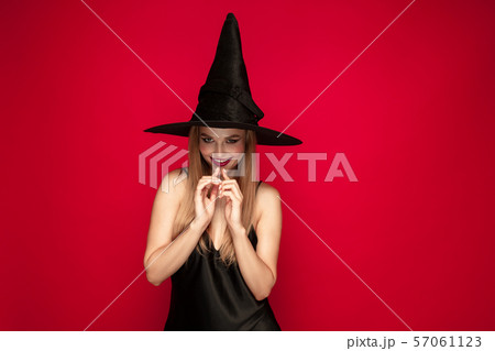 Young woman in hat as a witch on red background 57061123