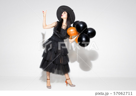 Young woman in hat and dress as a witch on white background 57062711