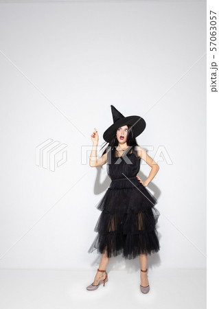 Young woman in hat and dress as a witch on white background Young woman in hat and dress as a witch on white background 57063057