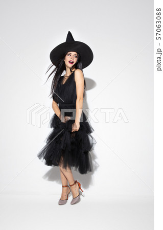 Young woman in hat and dress as a witch on white background 57063088