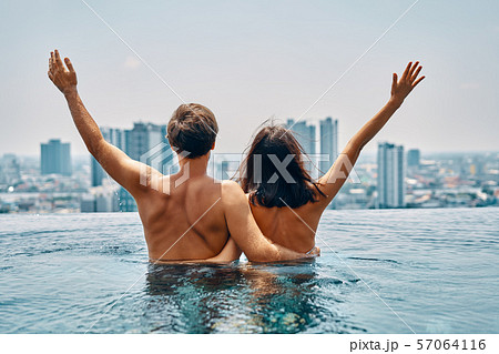 Young happy couple in love with arms up having fun in swimming pool Young happy couple in love with arms up having fun in swimming pool 57064116