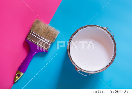 Purple brush with open can of white paint on blue 57066427