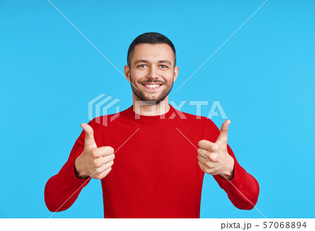 Happy handsome man showing thumbs up sign on blue background Happy handsome man showing thumbs up sign on blue background 57068894