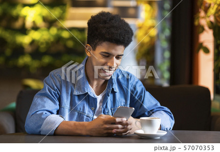 Smiling black teen guy chatting on cellphone with girl Smiling black teen guy chatting on cellphone with girl 57070353