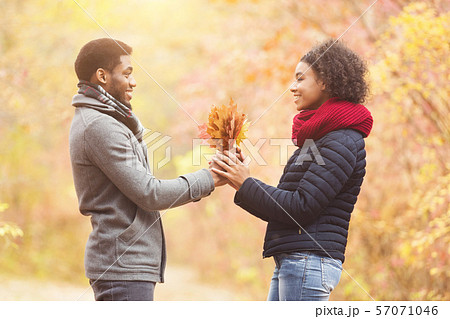 Romantic man giving girlfriend bunch of maple leaves 57071046