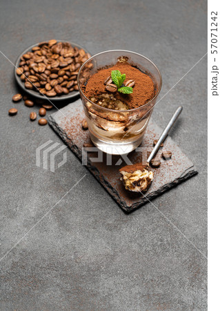 Portion of Classic tiramisu dessert in a glass cup on dark concrete background Portion of Classic tiramisu dessert in a glass cup on dark concrete background 57071242