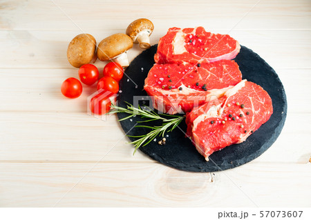 Three pieces of juicy raw beef on a stone cutting Three pieces of juicy raw beef on a stone cutting 57073607