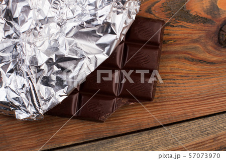 Close up of chocolate bar wrapped in silver foil. 57073970