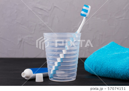 Glass with toothbrush, toothpaste and towel. 57074151