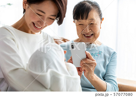 スマホで孫の写真を撮る母 57077080