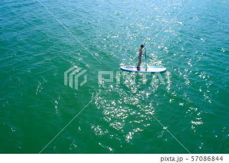 Aerial drone birds eye view of young woman exercising sup board in turquoise tropical clear waters 57086844