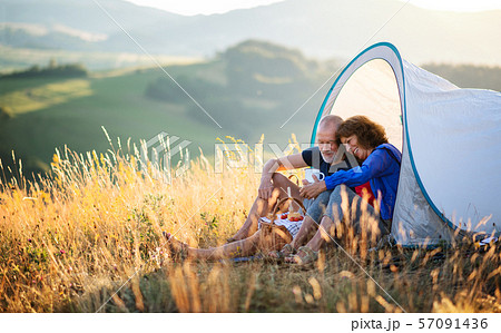 Senior tourist couple in love sitting in nature at sunset, resting. Senior tourist couple in love sitting in nature at sunset, resting. 57091436