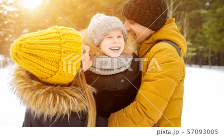 Mom and dad are cuddling and kissing their little son in winter park. 57093005