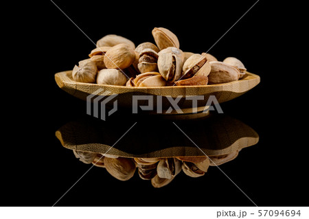 wooden plate of salted pistachio nuts 57094694