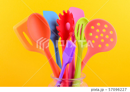 bright multi colored kitchen utensils on yellow background 57096227