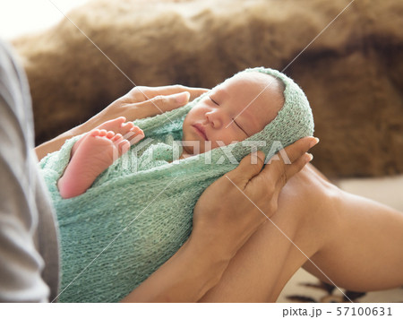 woman holding a newborn baby on her legs 57100631