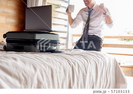 Happy businessman with raised hands in front of computer in bedroom hotel. 57103133