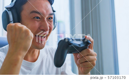 Eスポーツのイメージ コントローラーを片手に若者がゲームのプレイでエキサイティングしているシーンの写真素材