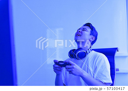 eスポーツのイメージ:コントローラーを片手に若者がゲームのプレイでエキサイティングしているシーン eスポーツのイメージ:コントローラーを片手に若者がゲームのプレイでエキサイティングしているシーン 57103417