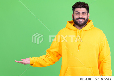 Happy young overweight bearded Indian man showing something 57107283