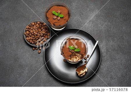 Portion of Classic tiramisu dessert in a glass cup on dark concrete background Portion of Classic tiramisu dessert in a glass cup on dark concrete background 57116078