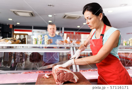 Girl seller cutting meat at the request customer 57116171