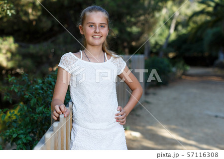 Smiling teen girl standing near fence in summer green park 57116308