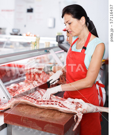 Adult woman seller carving of pig carcass Adult woman seller carving of pig carcass 57116437