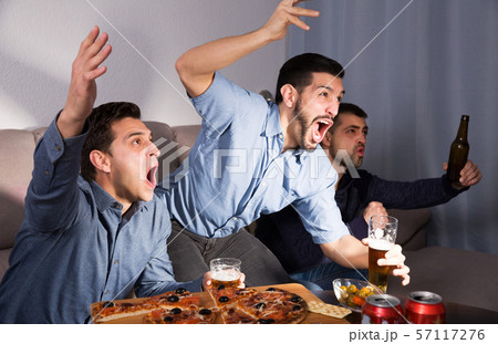 Exalted friends watching tv together at home Exalted friends watching tv together at home 57117276
