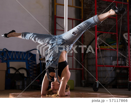 Young woman in ripped jeans performing pole dance Young woman in ripped jeans performing pole dance 57117866