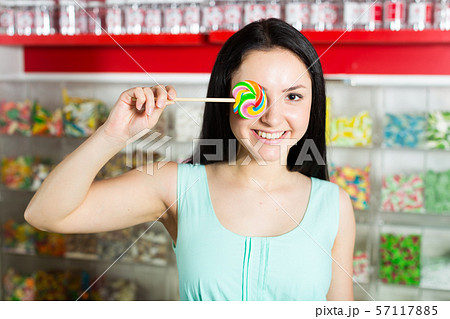 Smiling girl sucking lollypop in store 57117885