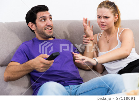 Couple on sofa quarreling because of TV remote 57118091
