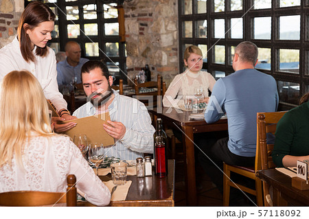 Waitress showing menu card to couple Waitress showing menu card to couple 57118092