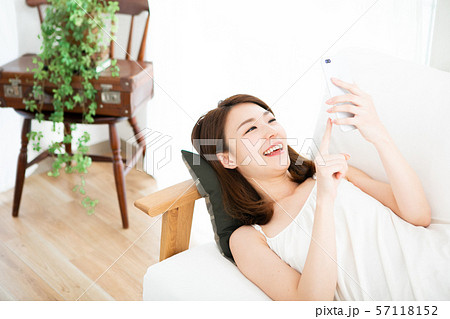 寝転がってスマホを使う笑顔の女性 57118152