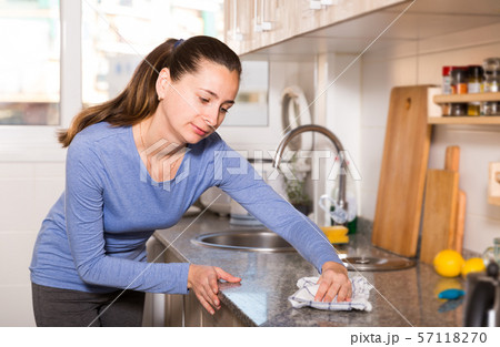 Smiling woman is cleaning surface on the kitchen at the home 57118270