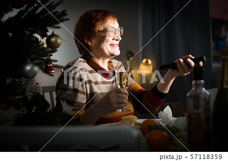 Senior woman with remote control in hand watching TV on New Year night 57118359