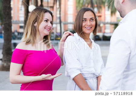 Young male is acquaintance with girls who are walking 57118918