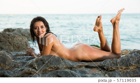 Relaxation young nude female lying on stones at sea shore 57119035