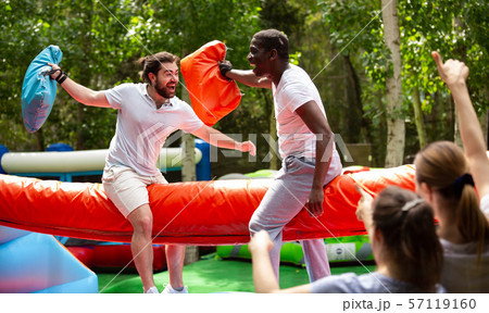 Cheerful pillow fight sitting on a log in an amusement park Cheerful pillow fight sitting on a log in an amusement park 57119160